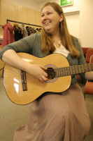 Rachel with guitar, smiling,